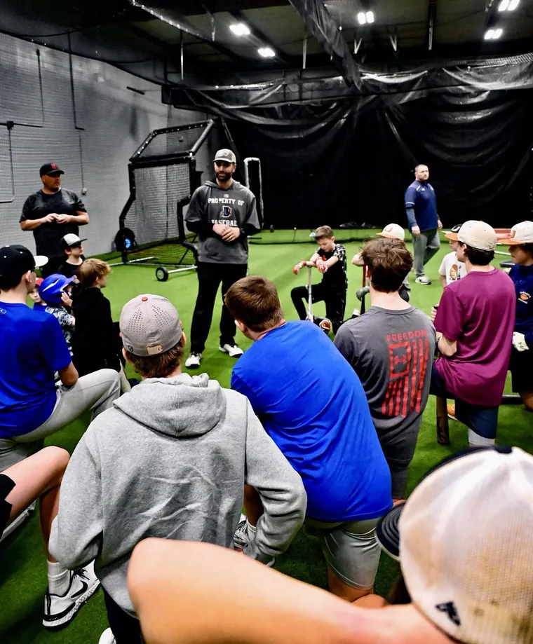 A coach talking to a group of young players on the turf at RCS Academy