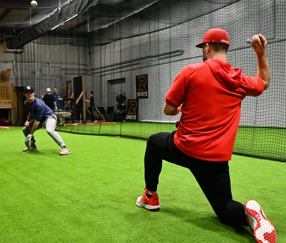 A coach throwing during an infield drill at RCS Academy